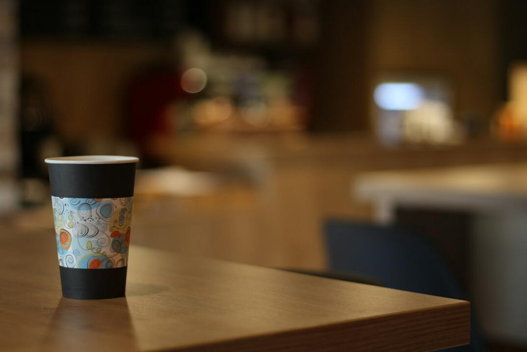 Smartphone on a desk showing a notification next to a coffee cup